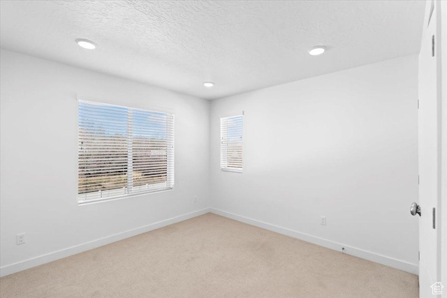 unfurnished room with recessed lighting, baseboards, light carpet, and a textured ceiling
