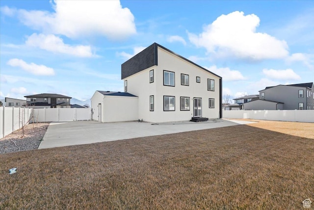rear view of property featuring a patio, a lawn, a fenced backyard, and stucco siding