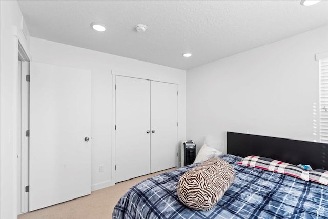 carpeted bedroom featuring a closet, recessed lighting, and a textured ceiling