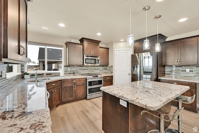 kitchen featuring light wood finished floors, light stone countertops, appliances with stainless steel finishes, and a kitchen island