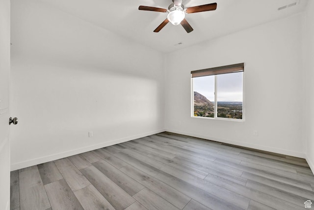 empty room featuring visible vents, baseboards, and wood finished floors