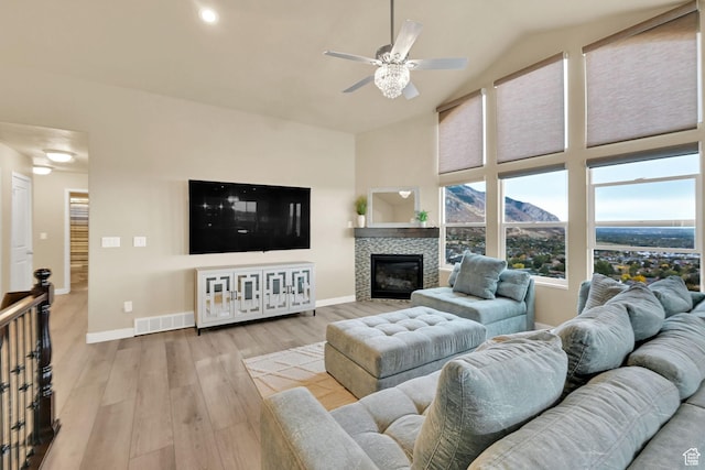 living area with visible vents, a fireplace, baseboards, and wood finished floors