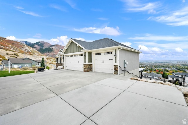view of home's exterior with fence, an attached garage, concrete driveway, board and batten siding, and a mountain view