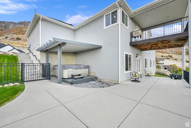 back of house featuring a patio area, fence, stucco siding, and a hot tub