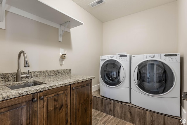 2409 W Rim Rock Dr, Stockton, UT 84071 - clothes washing area featuring visible vents, washer and clothes dryer, a sink, cabinet space, and light wood finished floors
