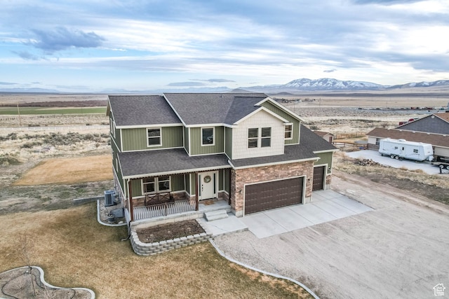 2409 W Rim Rock Dr, Stockton, UT 84071 - view of front facade featuring a mountain view, covered porch, concrete driveway, an attached garage, and a shingled roof