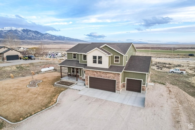 2409 W Rim Rock Dr, Stockton, UT 84071 - view of front of house featuring a porch, a mountain view, concrete driveway, and board and batten siding