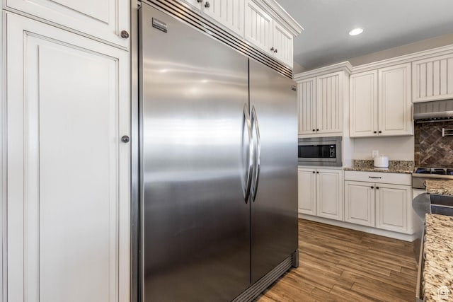 2409 W Rim Rock Dr, Stockton, UT 84071 - kitchen with light stone counters, built in appliances, wood finished floors, and white cabinets