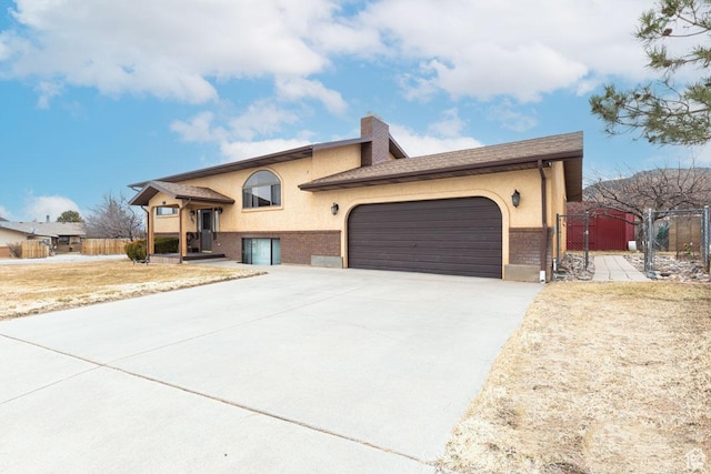 161 S Canyon Rd E, Parowan, UT 84761 - tri-level home featuring stucco siding, driveway, a gate, an attached garage, and a chimney