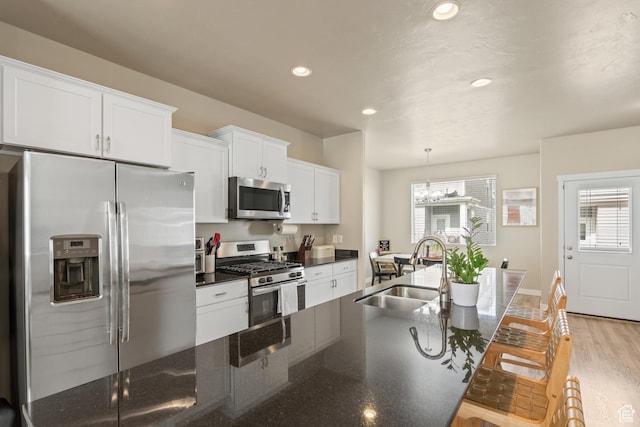 kitchen with white cabinets, appliances with stainless steel finishes, a sink, a wealth of natural light, and a kitchen bar