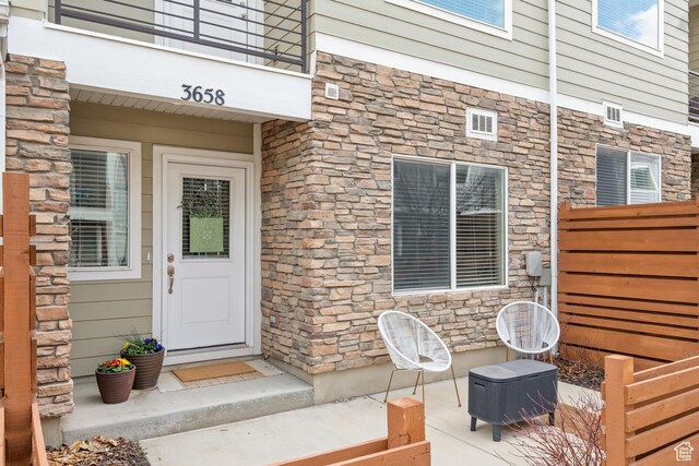 entrance to property featuring fence and stone siding