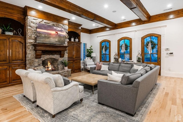living room featuring light wood finished floors, baseboards, beam ceiling, a stone fireplace, and recessed lighting