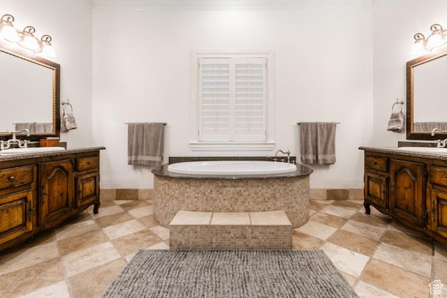 bathroom featuring two vanities, a bath, and a sink