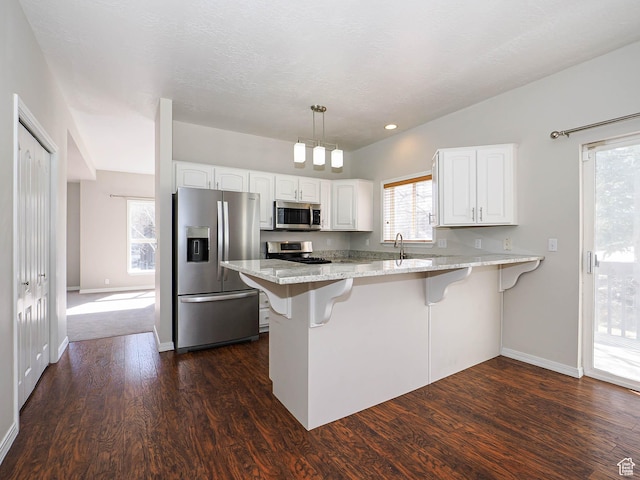 8004 Mustang Loop Rd, Park City, UT 84098 - kitchen with a kitchen bar, light stone counters, white cabinetry, stainless steel appliances, and a peninsula