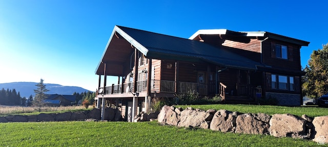 view of side of home with a porch, a mountain view, metal roof, and a yard