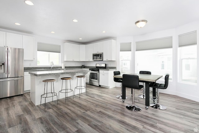 kitchen with a kitchen breakfast bar, a kitchen island, appliances with stainless steel finishes, and white cabinetry