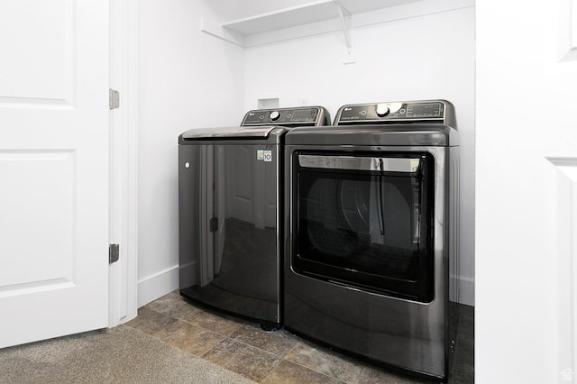laundry room with laundry area, stone finish floor, separate washer and dryer, and baseboards