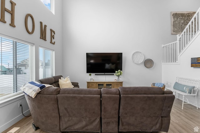 7382 W Butter Hollow Cir, Herriman, UT 84096 - living area featuring a towering ceiling, healthy amount of natural light, light wood-type flooring, and baseboards