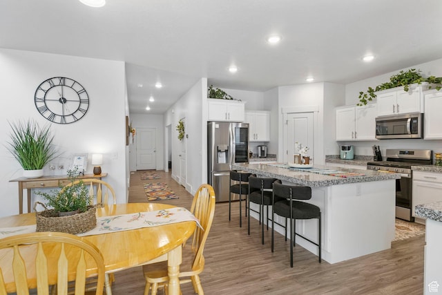 7382 W Butter Hollow Cir, Herriman, UT 84096 - kitchen with appliances with stainless steel finishes, a kitchen island, white cabinetry, light wood-style floors, and recessed lighting