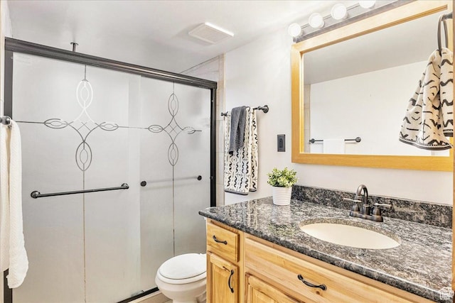 full bathroom with vanity, a shower stall, toilet, and visible vents