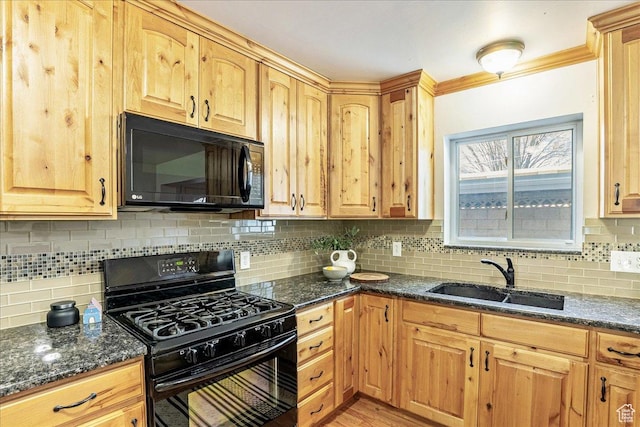 kitchen with dark stone countertops, black appliances, crown molding, and a sink
