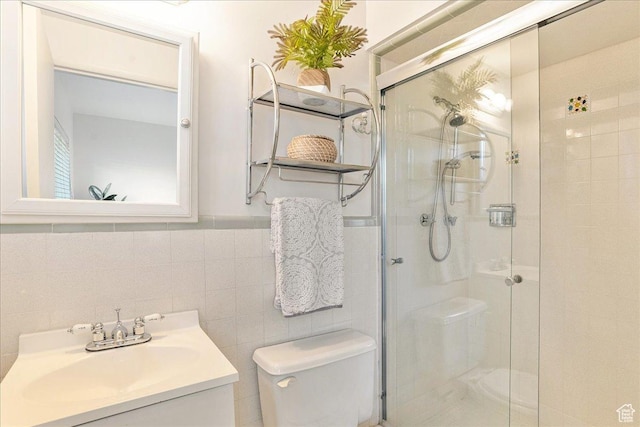 bathroom with toilet, vanity, wainscoting, a stall shower, and tile walls