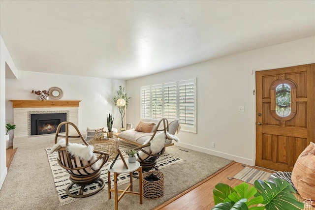 living area featuring a glass covered fireplace, baseboards, and wood finished floors