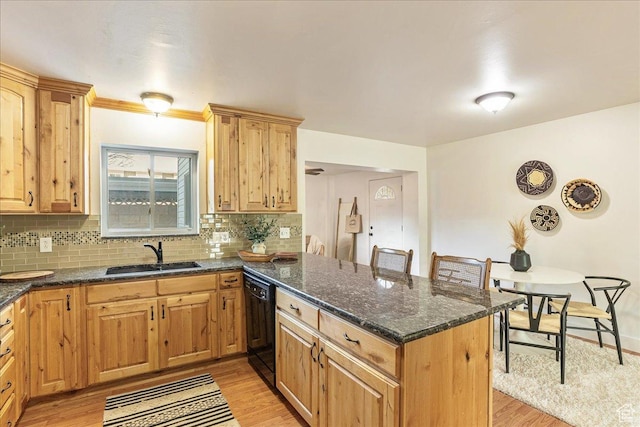 kitchen with a peninsula, light wood-style flooring, a sink, decorative backsplash, and black dishwasher