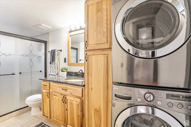 clothes washing area featuring light tile patterned flooring, laundry area, stacked washer and clothes dryer, and a sink