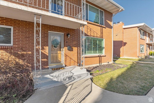 property entrance featuring a balcony and brick siding