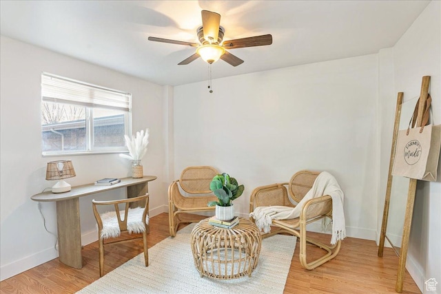 sitting room with baseboards, ceiling fan, and light wood finished floors
