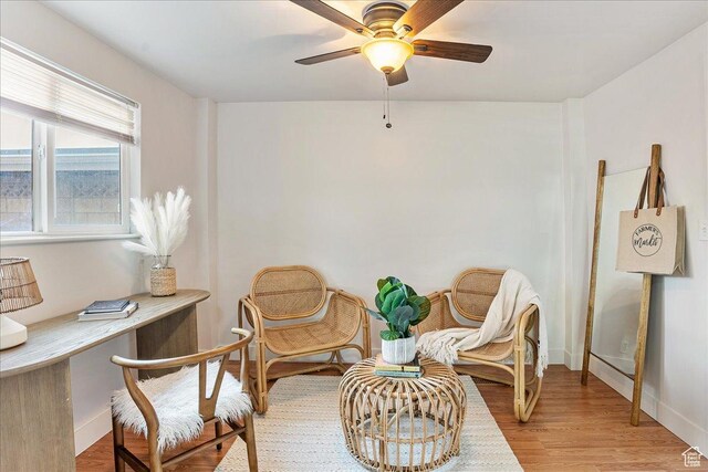 living area with baseboards, a ceiling fan, and wood finished floors