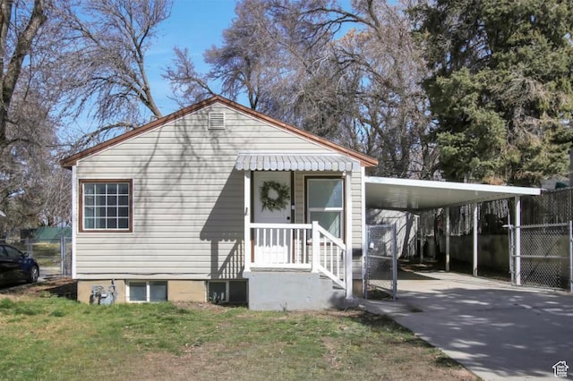 view of front of home with an attached carport, concrete driveway, a front yard, and fence