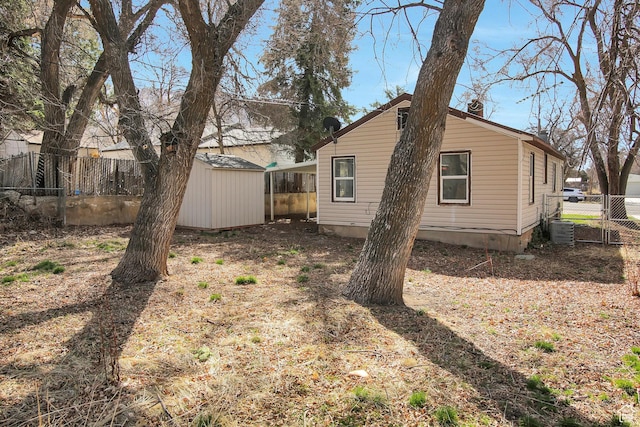 1278 E 22nd St S, Ogden, UT 84401 - rear view of property with an outbuilding, cooling unit, a fenced backyard, a chimney, and a storage shed