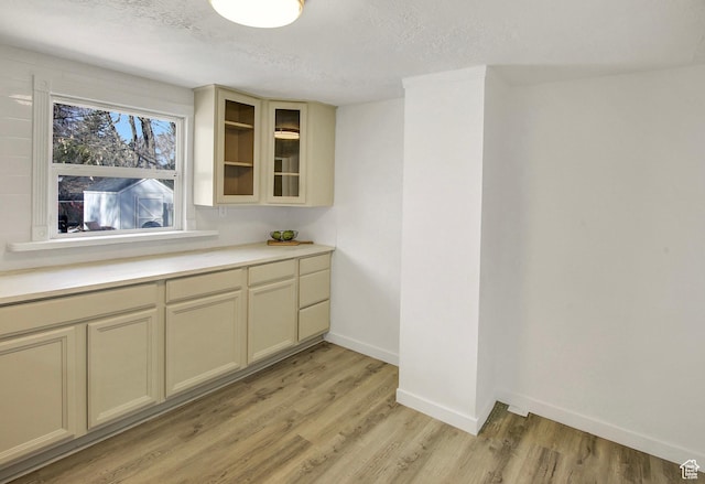 1278 E 22nd St S, Ogden, UT 84401 - kitchen featuring light wood-style flooring, a textured ceiling, light countertops, glass insert cabinets, and baseboards