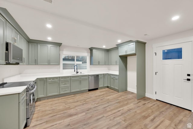 kitchen featuring recessed lighting, green cabinets, stainless steel appliances, and a sink