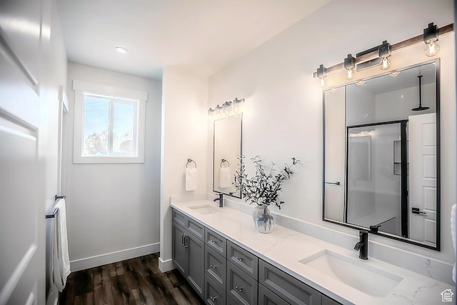 full bath featuring double vanity, wood finished floors, baseboards, and a sink