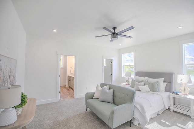 bedroom with light colored carpet, baseboards, multiple windows, and ensuite bathroom