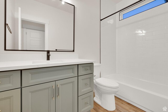 full bath featuring wood finished floors, toilet, vanity, and bathing tub / shower combination