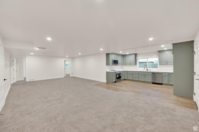 kitchen with stainless steel appliances, light carpet, and recessed lighting