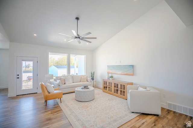 living room featuring lofted ceiling, wood finished floors, visible vents, and a ceiling fan