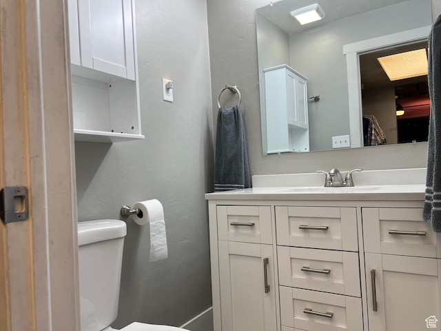 bathroom featuring a textured wall, toilet, and vanity