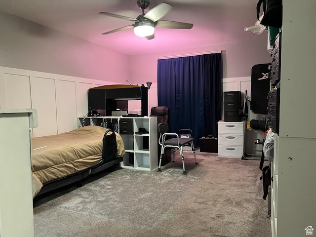 bedroom featuring a wainscoted wall, ceiling fan, carpet floors, and a decorative wall