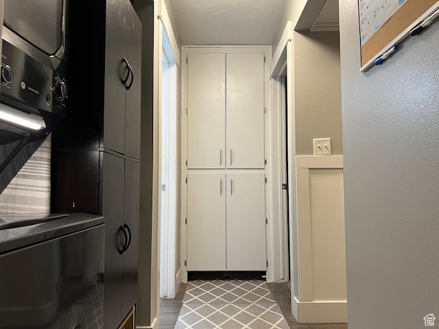 clothes washing area with stacked washer and dryer, a textured wall, and laundry area
