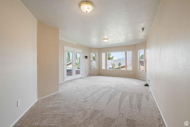 empty room with visible vents, baseboards, carpet floors, a textured wall, and a textured ceiling