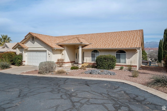view of front of property with stucco siding, a garage, driveway, and a tile roof