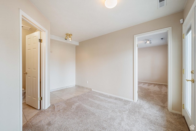 empty room with light tile patterned flooring, light colored carpet, and visible vents