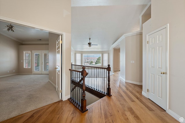 hall with an upstairs landing, wood finished floors, baseboards, and ornamental molding