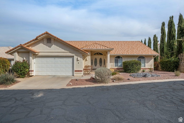 mediterranean / spanish house featuring a tile roof, stucco siding, concrete driveway, and a garage