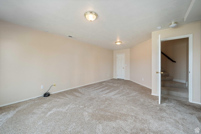 carpeted empty room with stairs, baseboards, and visible vents